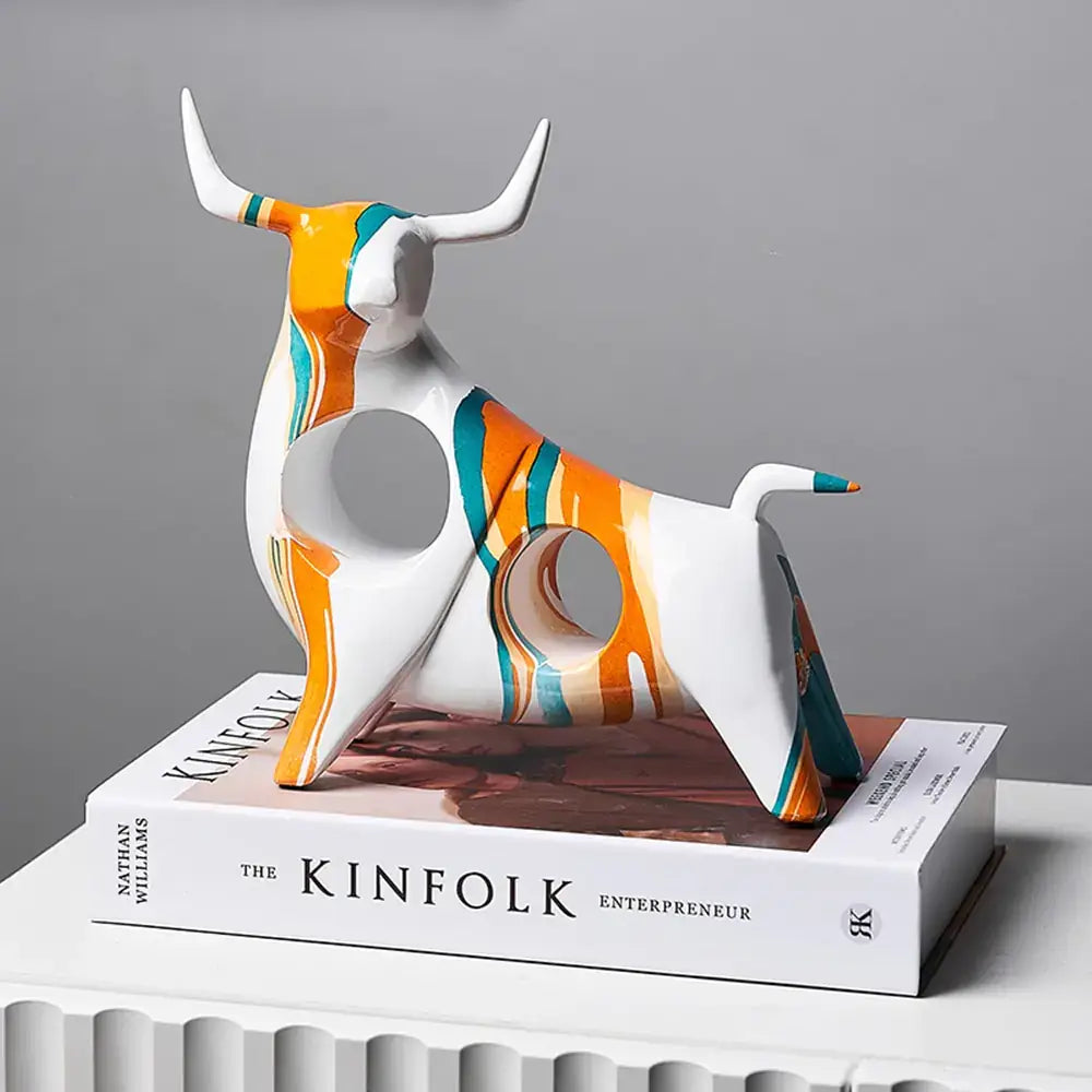 Modern Art Graffiti Cow Figurine with colorful design on a white background displayed on a stack of books