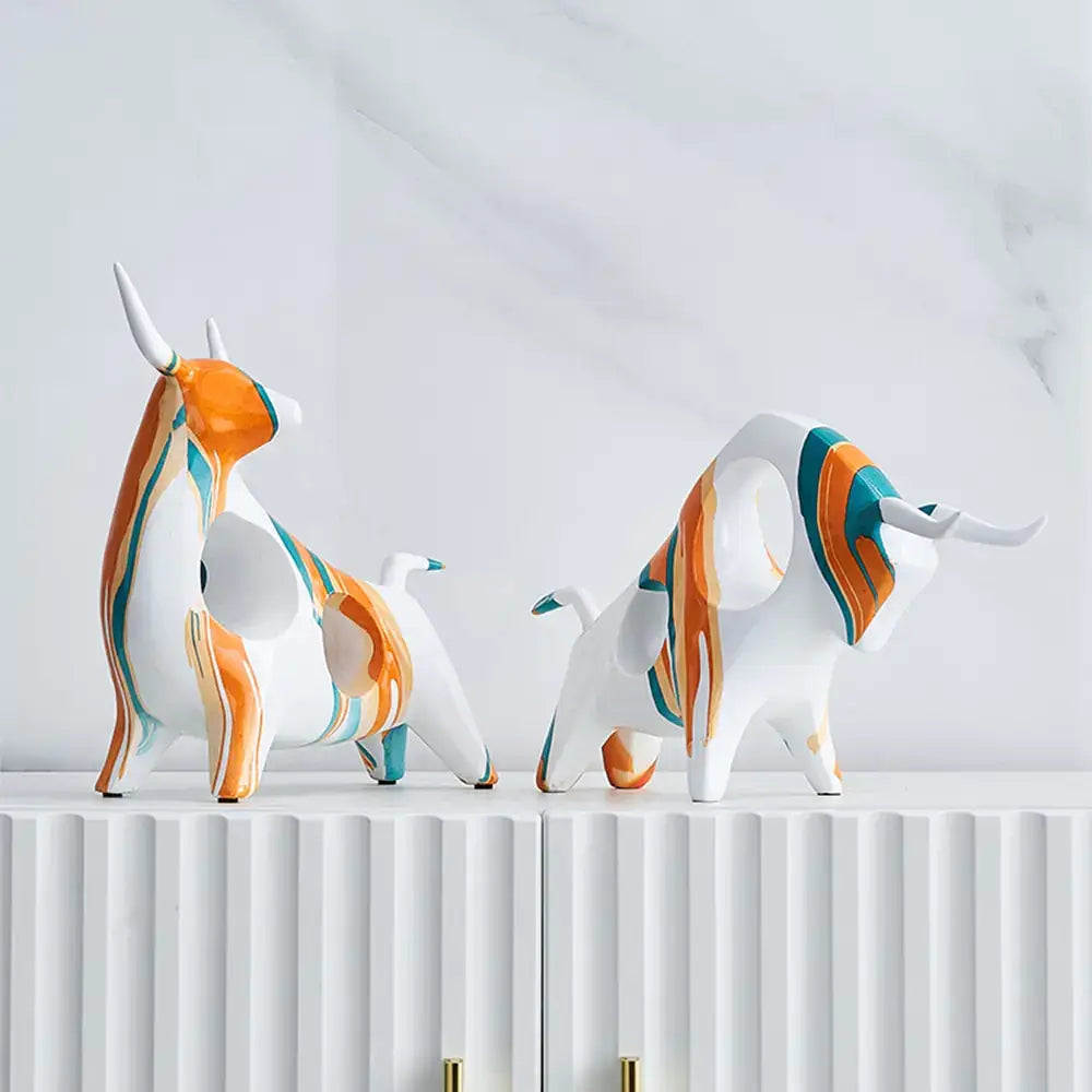 Modern Art Graffiti Cow Figurines with bold, colorful designs displayed on a white cabinet against a marble background